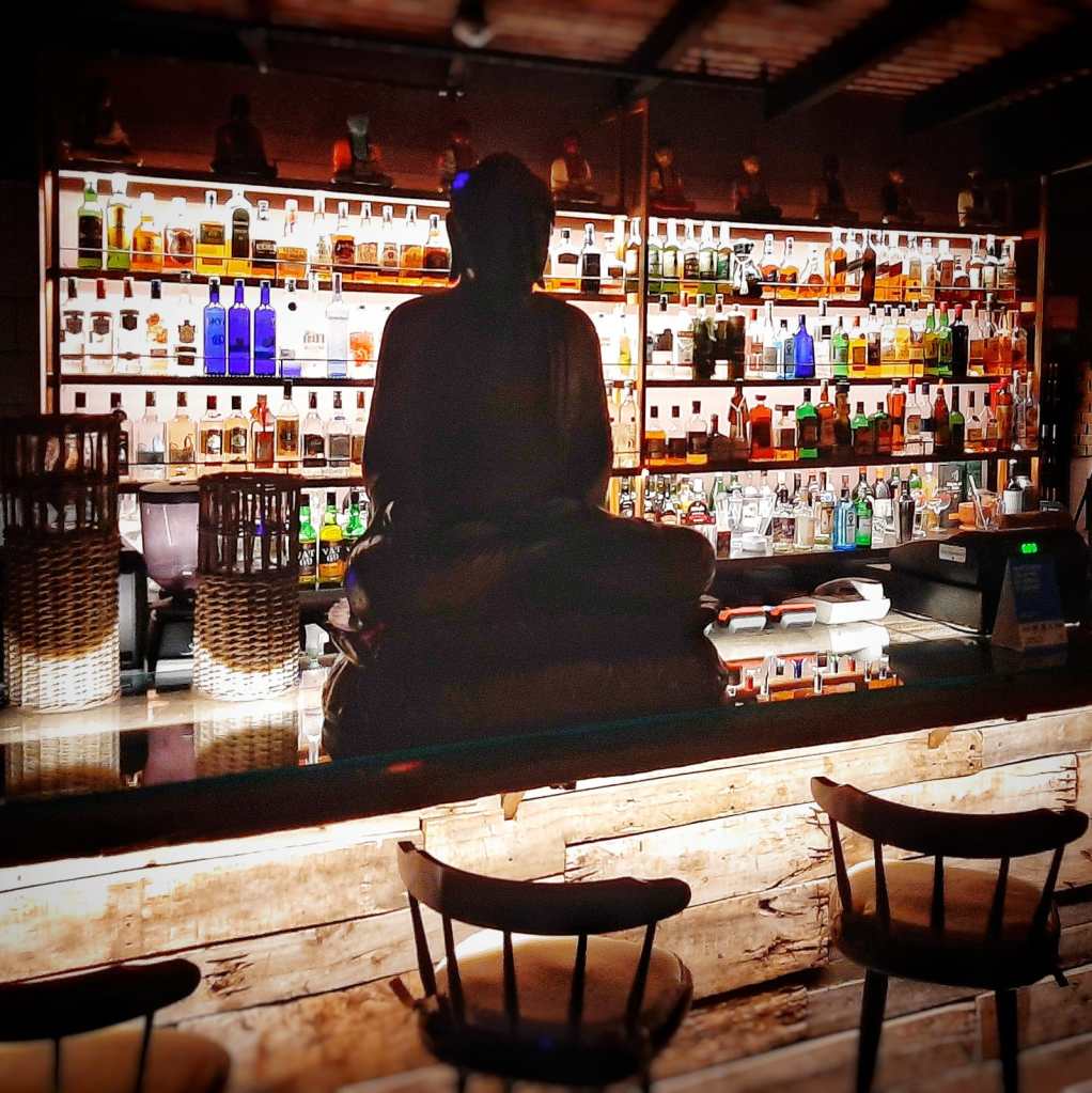 Bar de Sofía con estantería de destilados y silueta de Buda